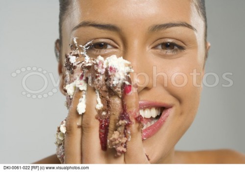 portrait-of-a-young-woman-eating-cake-icing-and-smiling